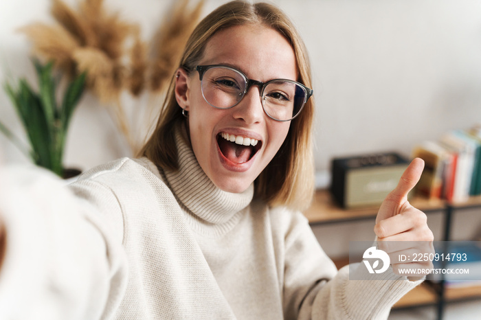 Photo of smiling attractive woman taking selfie and showing thumb up