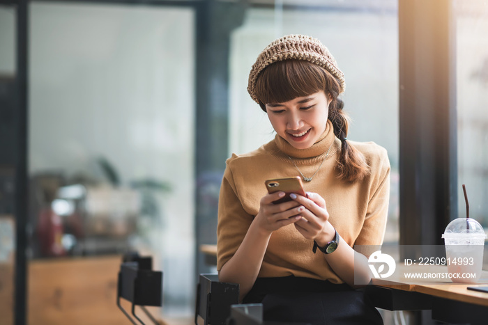 Young asian woman enjoying playing on their phone at café.