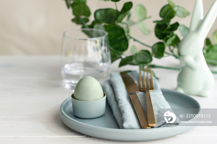 Happy Easter concept. Close up of Easter  Egg in mint green plate with  napkin. Scandinavian style  