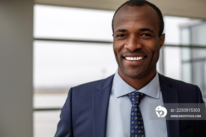 Good mood. Portrait of positive delighted young african businessman in suit is standing and looking 