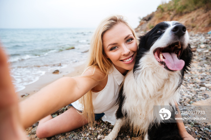 快乐的女人在海滩上和狗自拍
