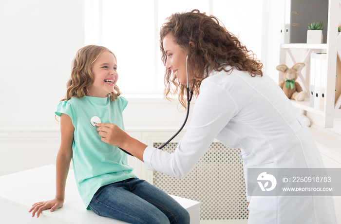 Doctor with stethoscope listening to child breathing in hospital