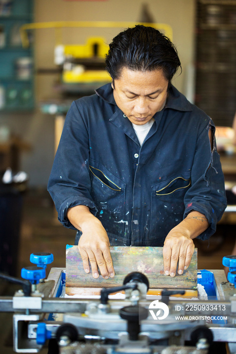 Worker pressing ink on frame in workshop