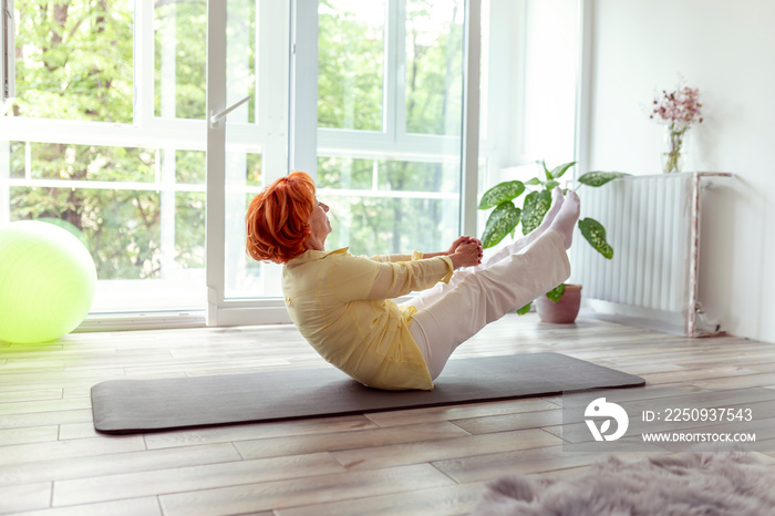 Active senior woman holding boat yoga pose