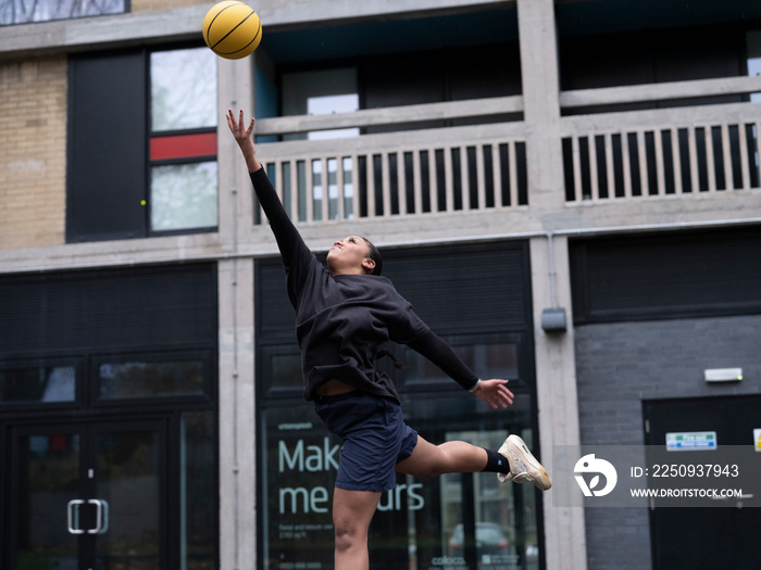 Teenage girl playing basketball outdoors