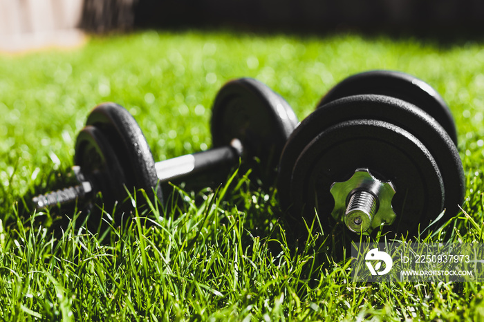 keeping fit and exercising outdoor, set of heavy dumbbells on green grass lawn in a backyard under d