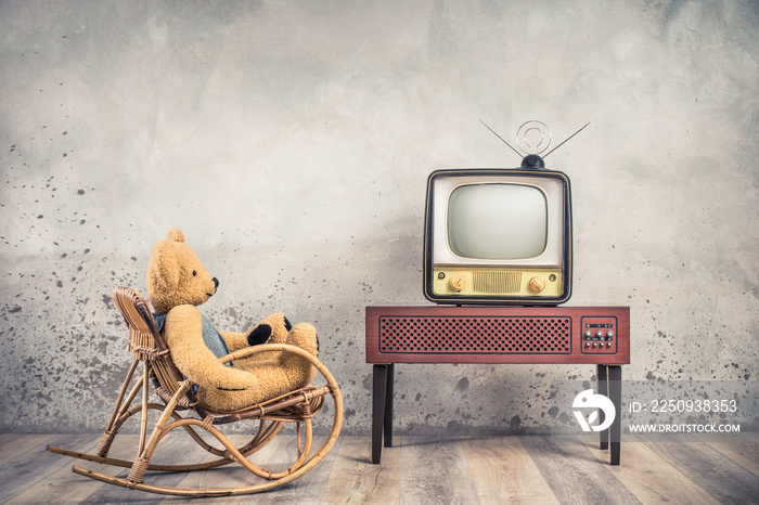 Retro Teddy Bear toy on rocking chair watching old outdated analog television receiver from 50s on w