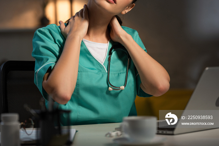 夜班时身穿制服的护士坐在桌子旁颈部疼痛的裁剪图