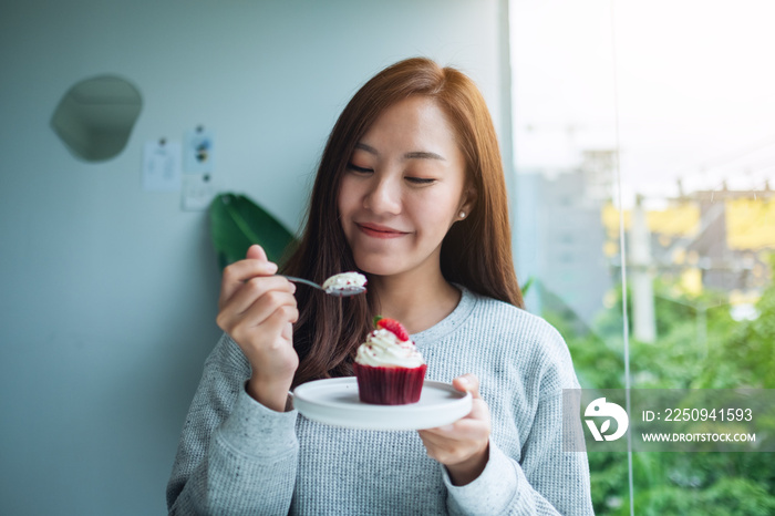 一个美丽的亚洲女人喜欢吃红色天鹅绒杯蛋糕