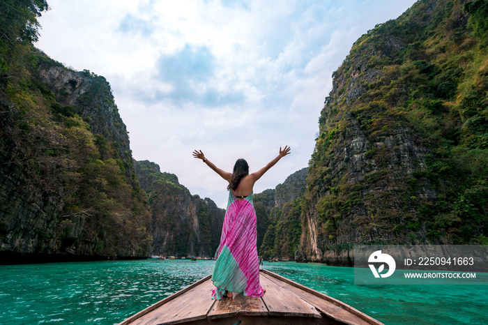 happy Asian woman traveler standing on a long-tailed boat looking at beautiful natural Pileh lagoon 