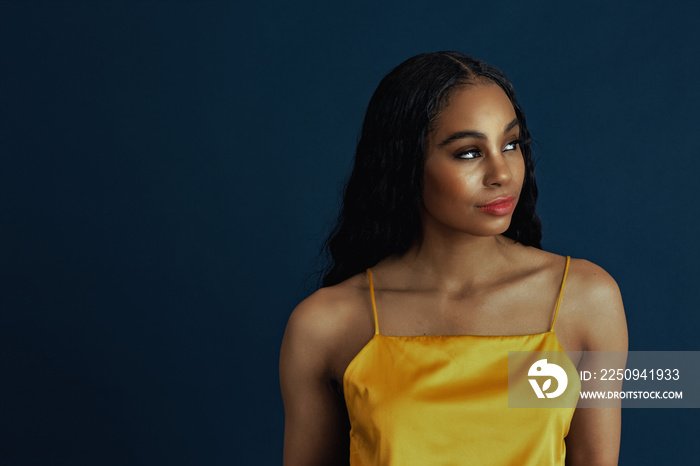 Portrait of a beautiful young woman with black curly hair wearing yellow top looking off camera