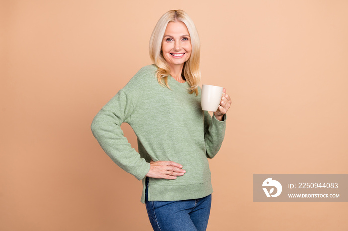 Photo of pretty adorable retired woman wear green sweater drinking hot beverage isolated beige color