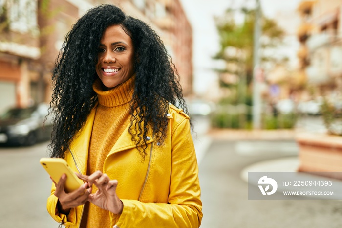 中年非裔美国妇女在城市里用智能手机开心地微笑。