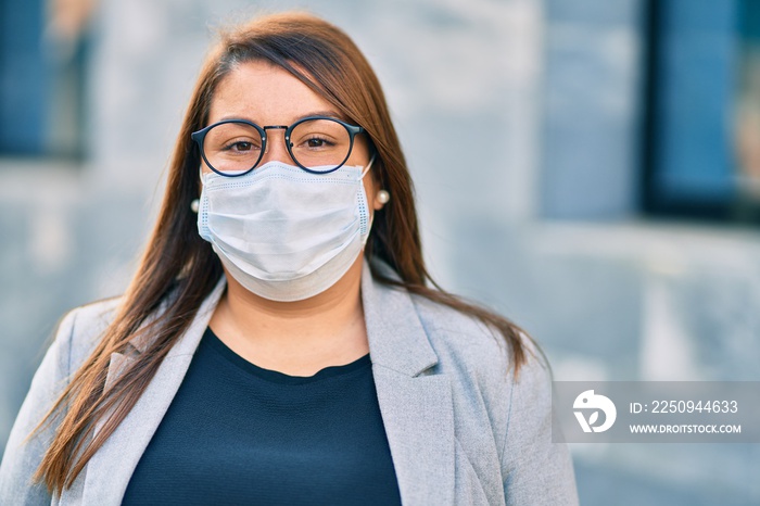 年轻的西班牙大码女商人戴着医用口罩站在城市里。