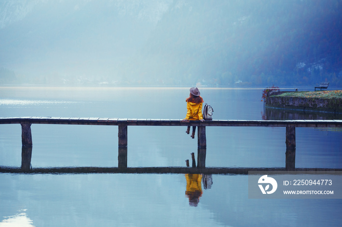 tourist girl in a hat and with a backpack stands on a wooden bridge