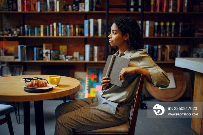 Female student reads book in library cafe