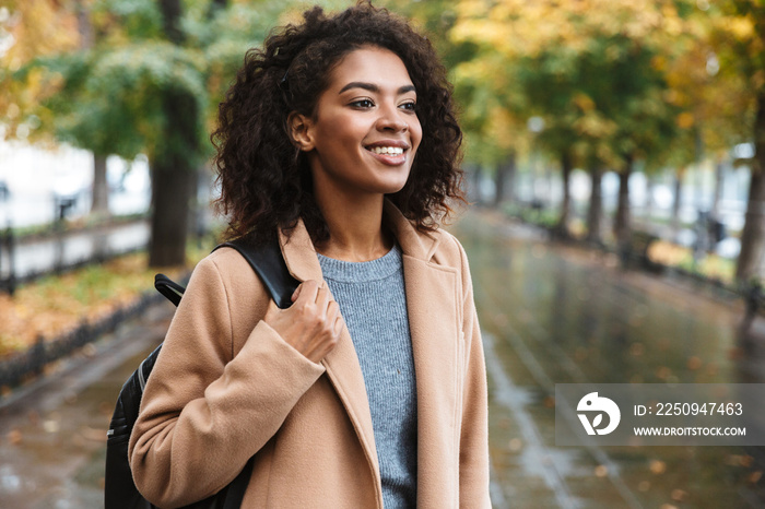 Beautiful young african woman wearing coat walking outdoors