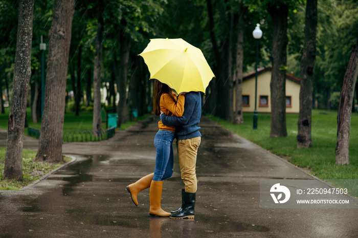 Love couple kissing in park, summer rainy day