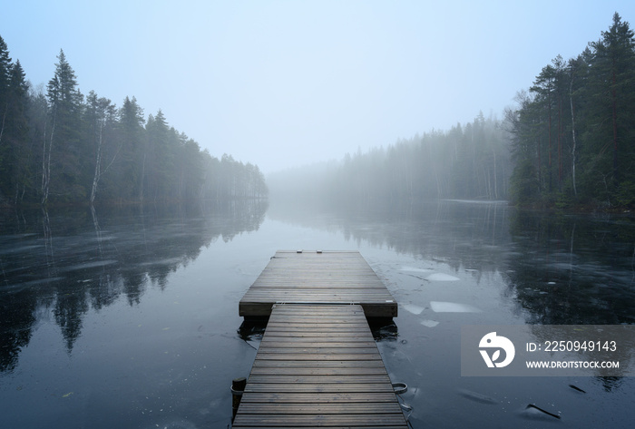 Foggy landscape with calm lake and pier. Mist over water. Foggy air. Early chilly morning in autumn.
