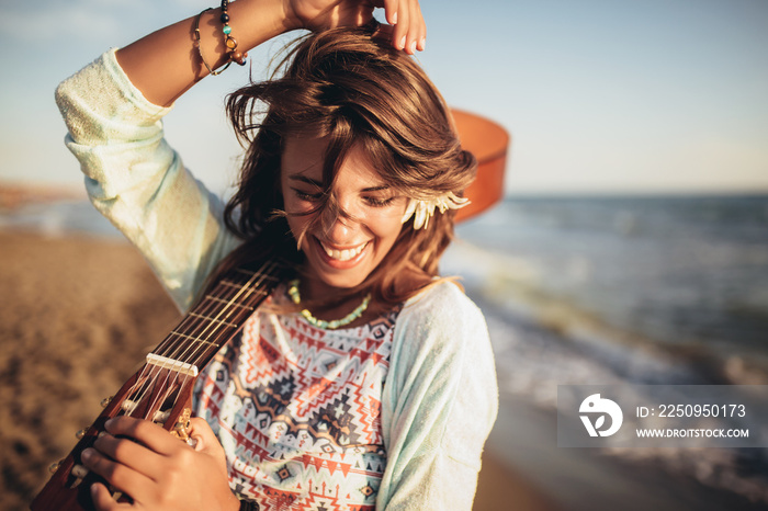 Cute girl walking on the beach holding a guitar in her hands.