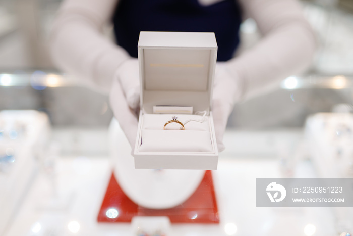 Female seller hands holds gold diamond ring in box