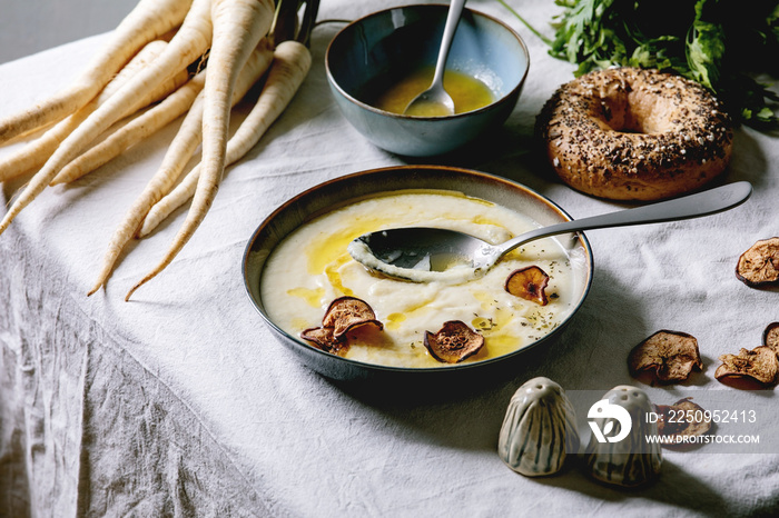 陶瓷碗里的欧防风奶油汤，黄油酱，晒干的梨，一捆新鲜的欧防风，百吉饼