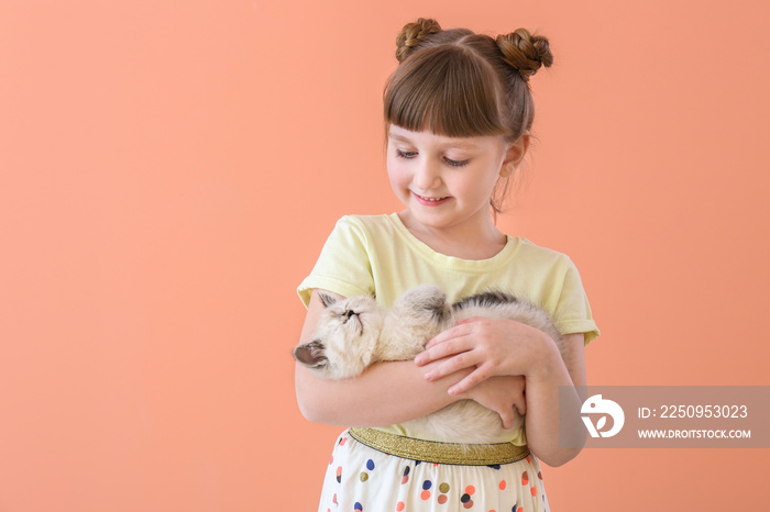 Girl with cute fluffy kitten on color background