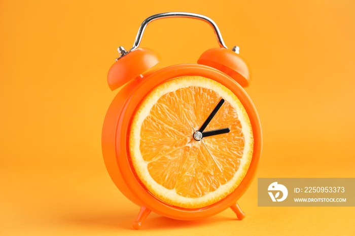 Creative alarm clock with citrus fruit on color background