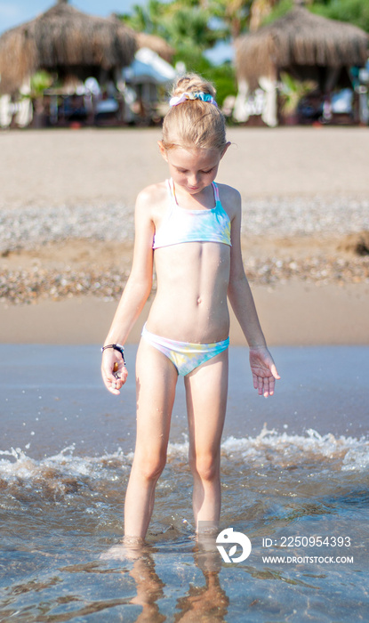 Little girl playing on the beach by the sea