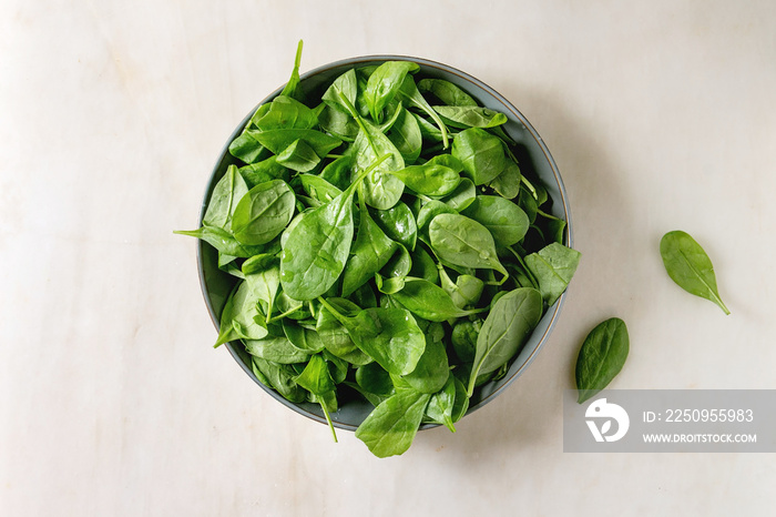 Bowl of fresh Baby spinach leaves over white marble background. Flat lay, copy space