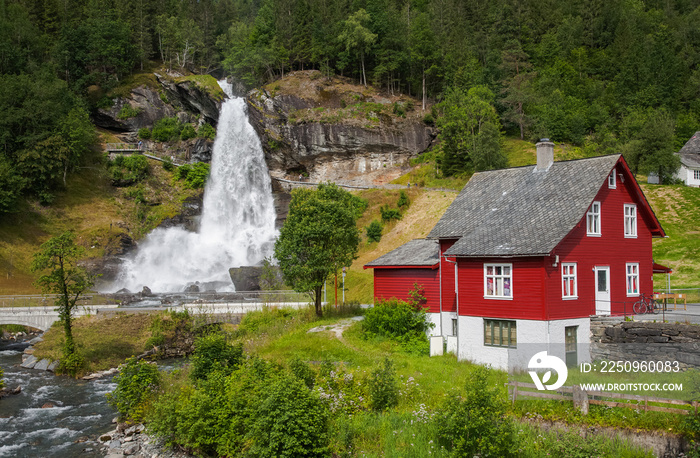 The Steinsdalsfossen waterfall and a red house in the foreground. Norway