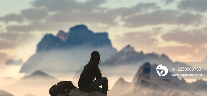 A girl on top of a hill in silence admires a tranquil landscape in the evening.