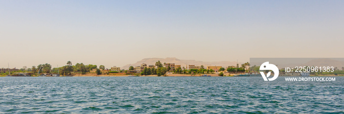 Residential buildings on the Nile river with sailboats in Luxor, Egypt