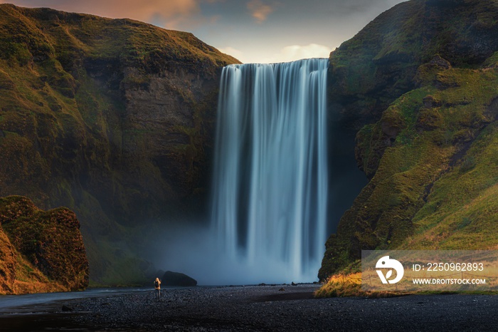 Beautiful shot of a waterfall surrounded by hills at sunset