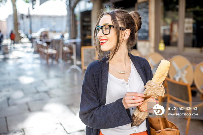 Young stylish woman buying a french baguette standing on the street in Lyon city