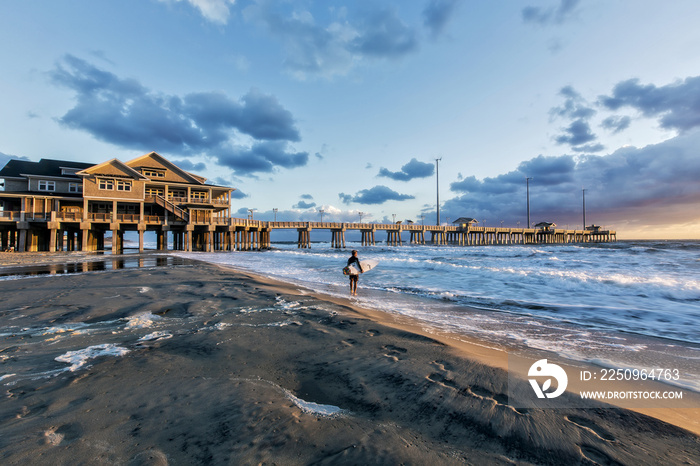 A surfer studying the waves just after sunise at Jeannettes Pier, Nags Head, N.C.