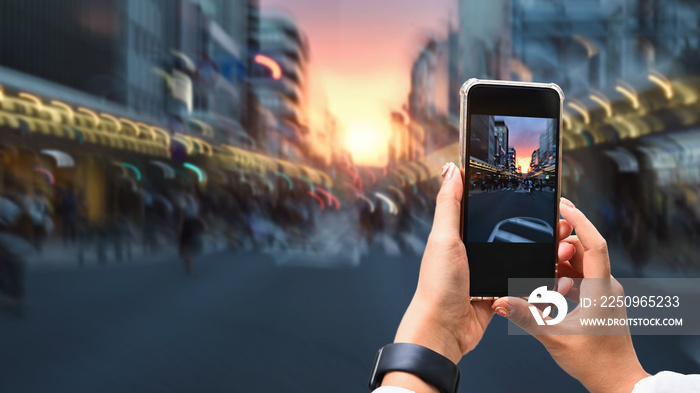 Close up image of woman hands taking a photo by use her smartphone  at dusk on pedestrian crossing.