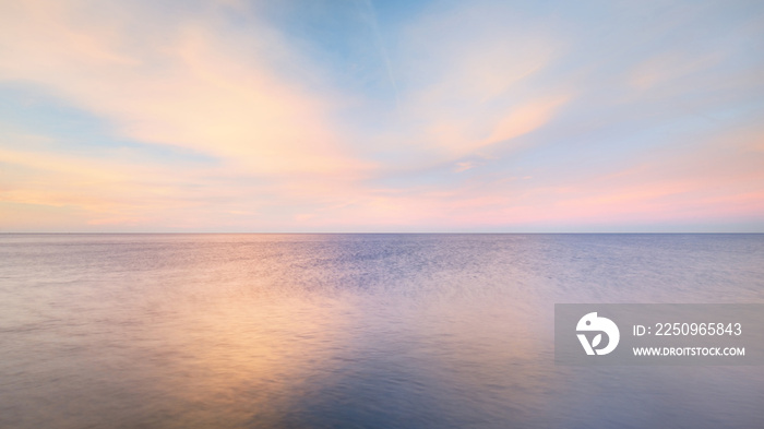 Baltic sea under the colorful sunset sky. Stunning seascape. Golden sunset light through the pink cl