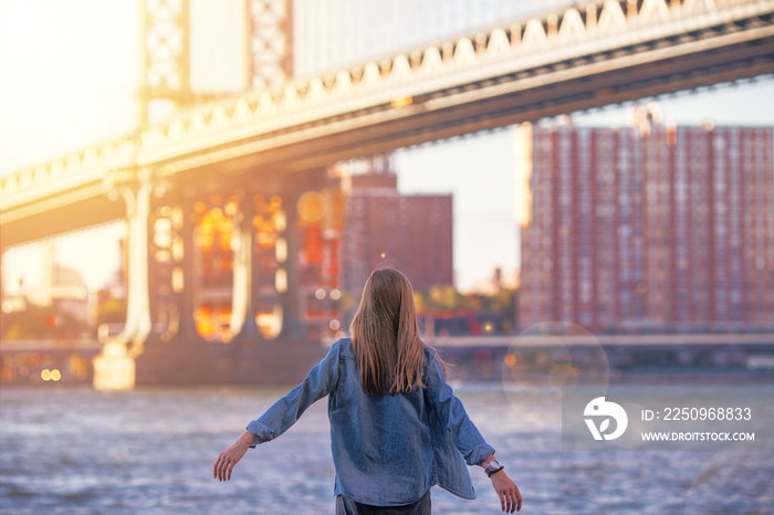 Woman standing near the river in New York, Brooklyn Bridge. - Image