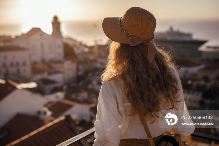 金发女人站在阳台上，带着se看着南欧城市的海岸景色