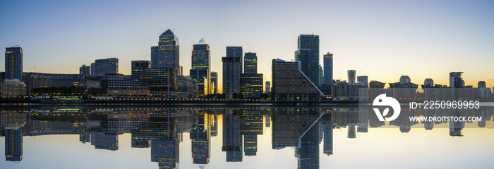 Panorama of Canary Wharf business district with water reflection at sunset