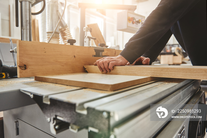 Manufacturing Relationships. Distributing Quality. Carpenter cutting wood on electric saw. Cropped i