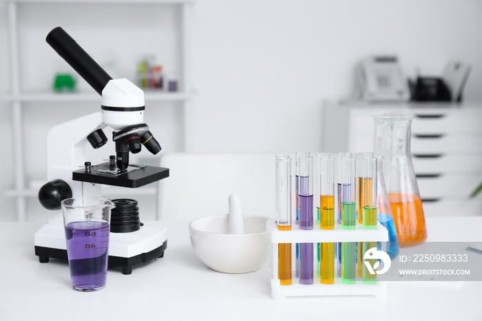 Modern microscope and chemical glassware on table in medical laboratory