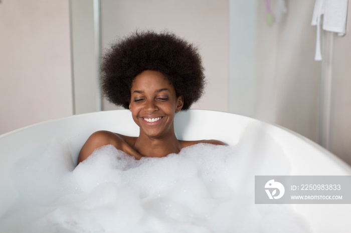 Portrait carefree young woman with afro enjoying bubble bath