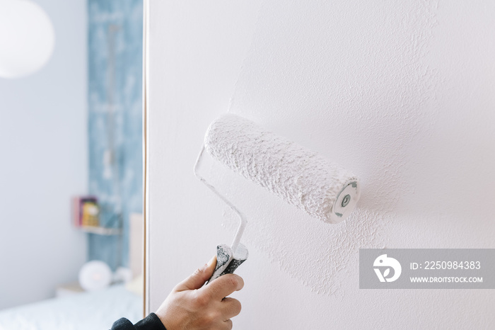 painting a wall in white with a roller