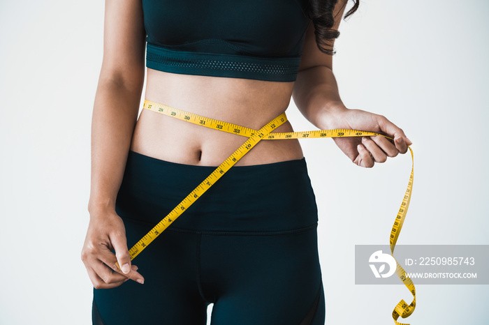 Close up shot of woman with slim body measuring her waistline and torso. Healthy nutrition and weigh