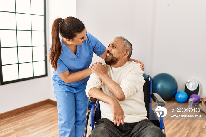 Senior man sitting on wheelchair and geriatric nurse at rehabilitation clinic