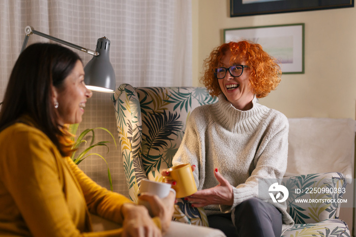 middle aged female friends having fun at home, drinking coffee and talking