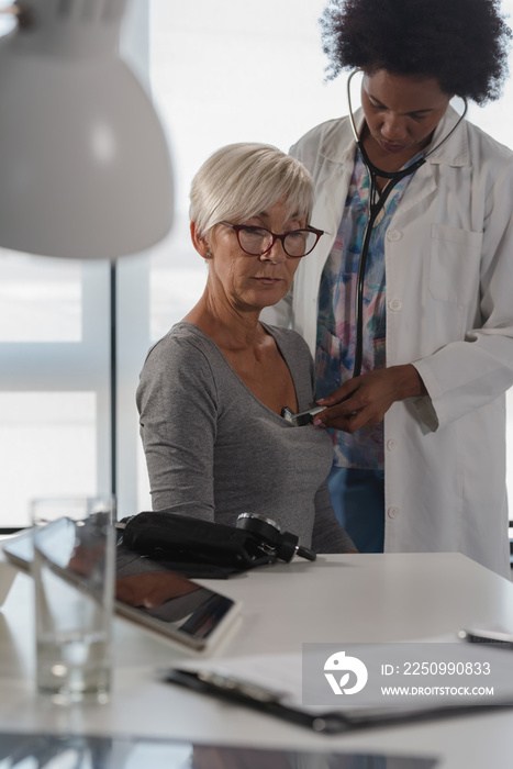 Female doctor examining elderly female patient. Heart and blood pressure checking. Periodic heart ex