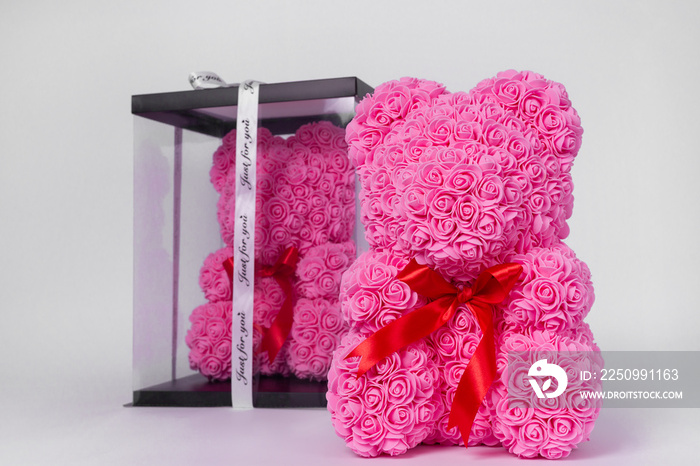 Pink teddy bear toy of foamirane roses. The same teddy in clear box with black paper cover on backgr